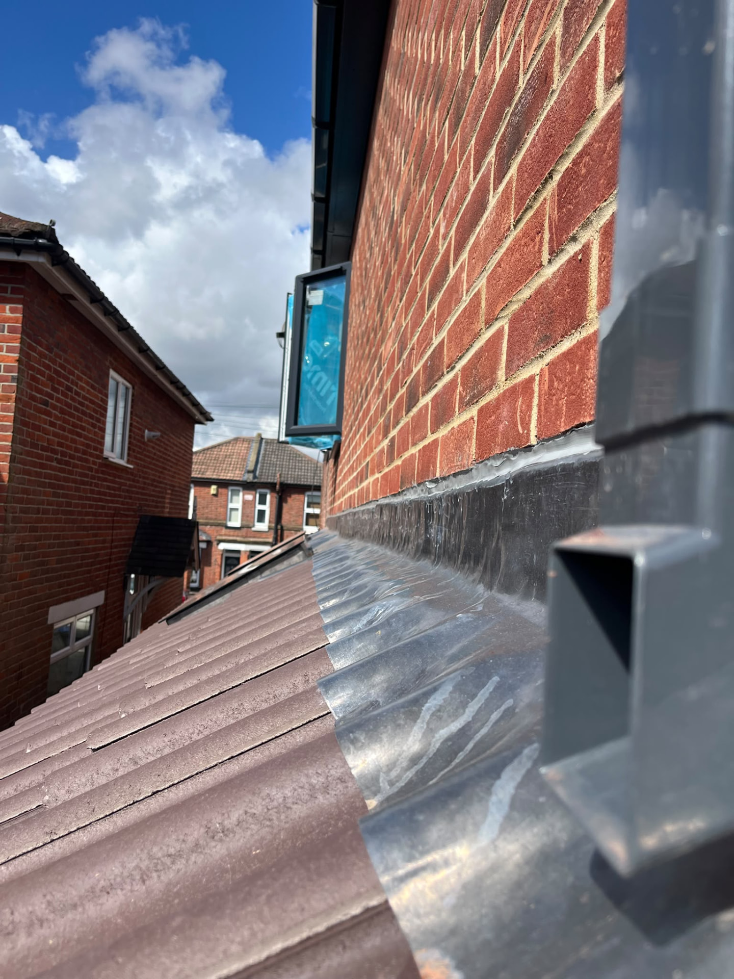 Lead flashing dressed between new roof tiles and brickwork on a BMS rebuild